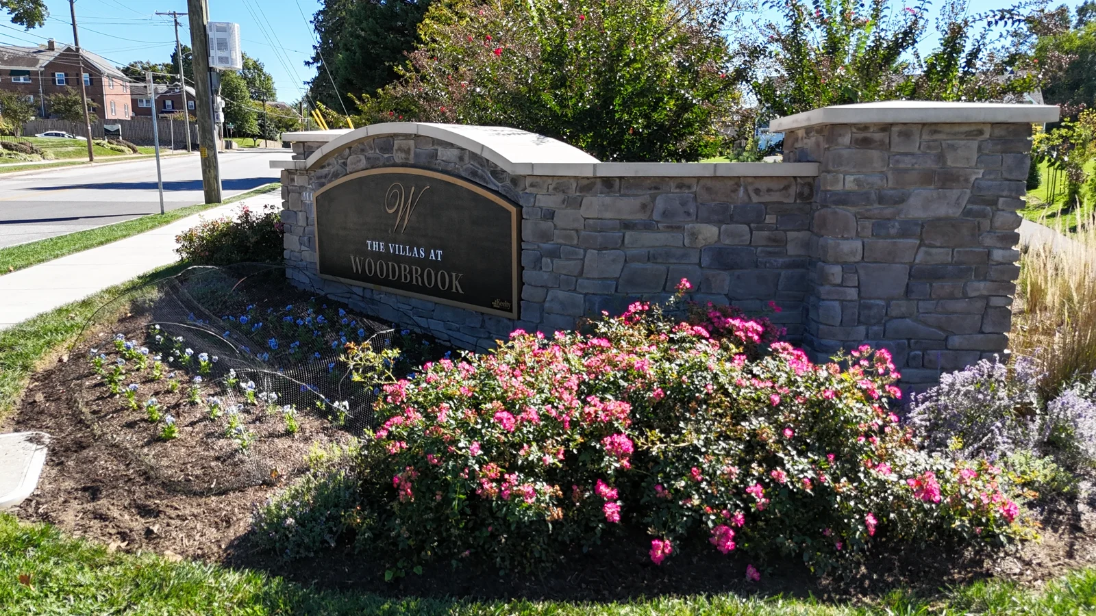 The Villas at Woodbrook stone entrance sign beside the walking path and landscaping